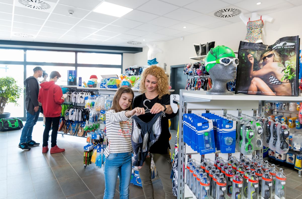 Zwei Frauen vergleichen Badeanzüge in einem Sportgeschäft mit Schwimmzubehör und Accessoires